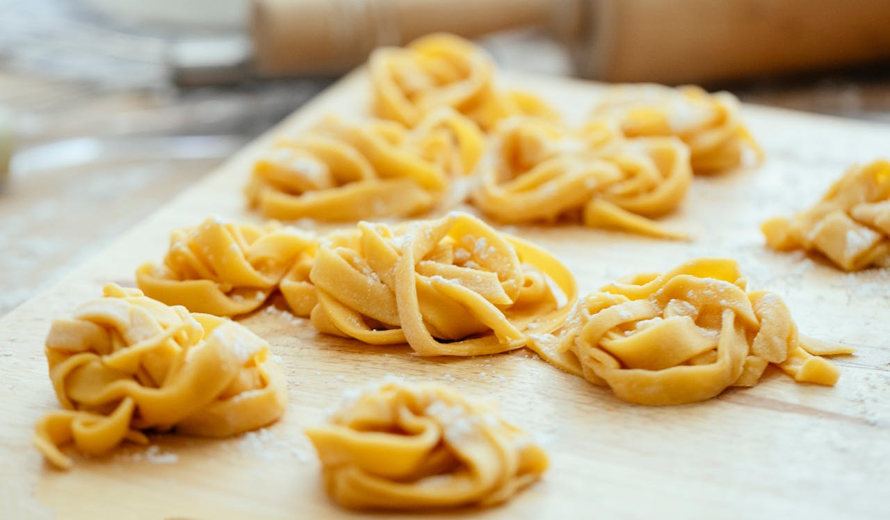 High angle of raw homemade pasta nests on floured wooden board in kitchen